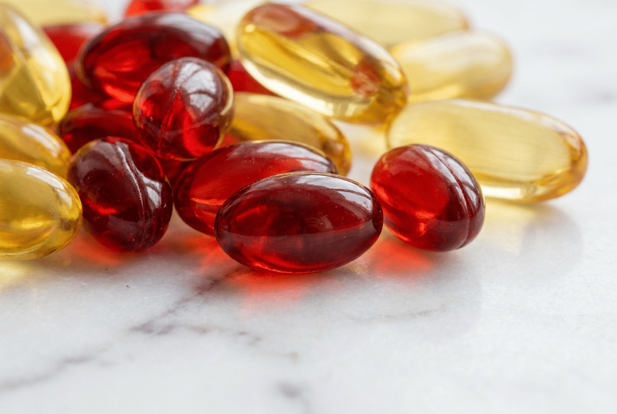 Rode krillolie softgels naast gele visolie capsules