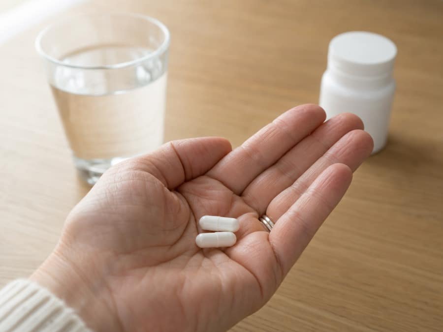 Twee capsules met een glas water