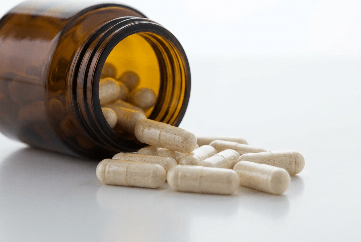Probiotica capsules vallen uit een donker glazen potje op een wit oppervlak